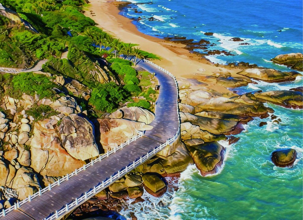 Broad paved Nanshan greenway winding over shoreline rocks beside the sea