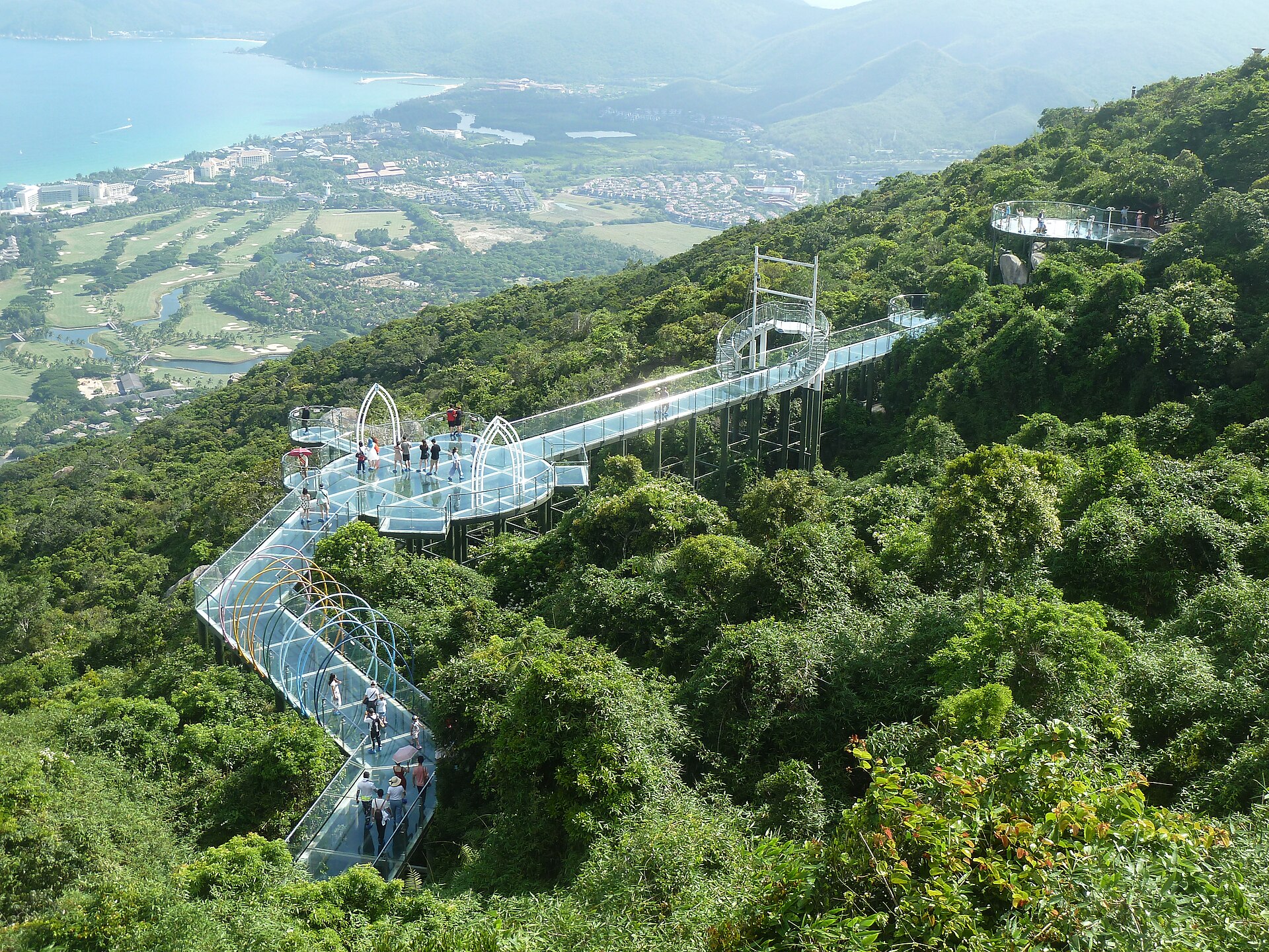 Glass skywalk winding through tropical forest above Yalong Bay