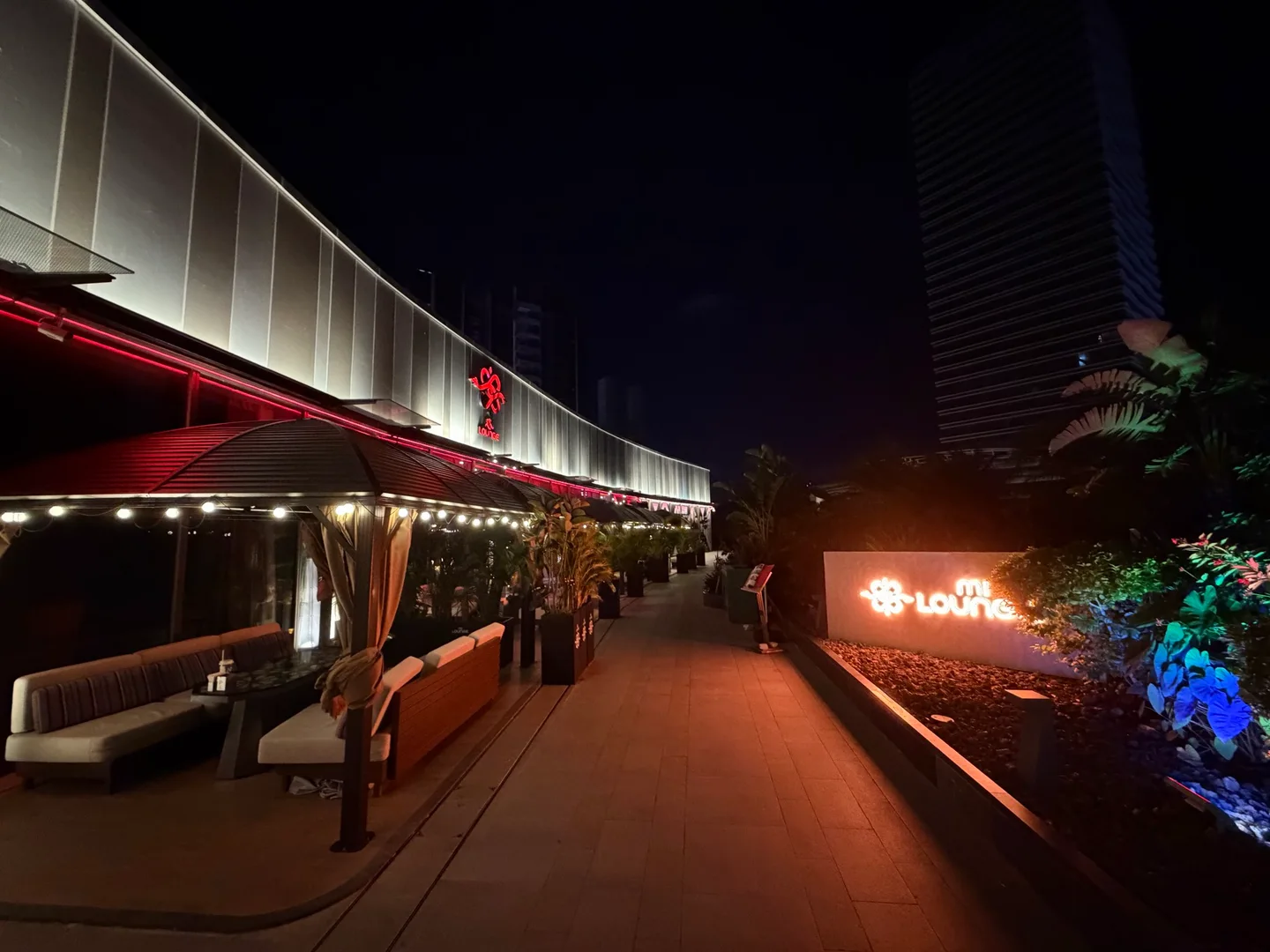 迷Lounge的发光入口招牌与带顶篷的露天沙发