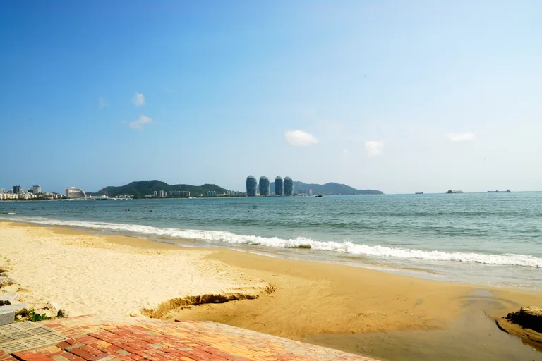 Small waves along a sandy shoreline with distant towers