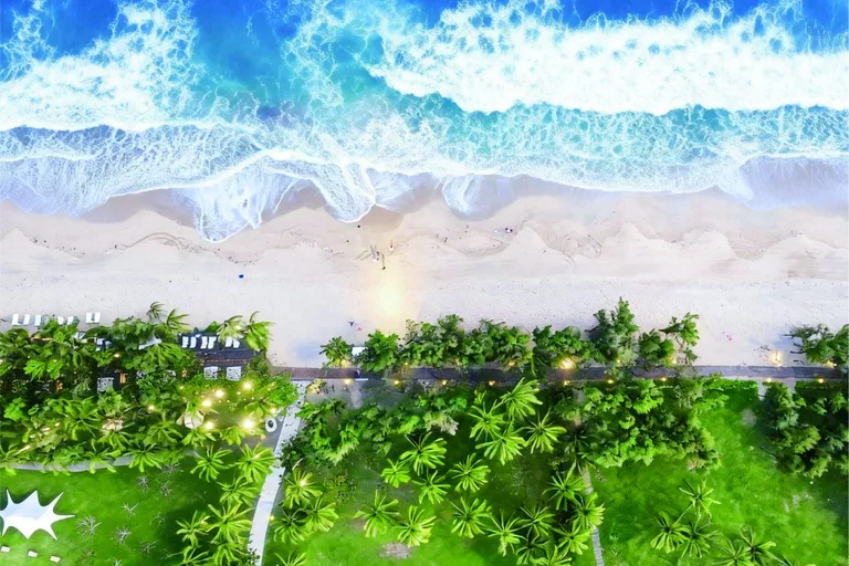 Waves meeting a sandy beach beside palms and a coastal path
