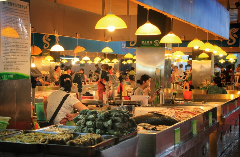 Shoppers and vendors among seafood stalls at Sanya First Market