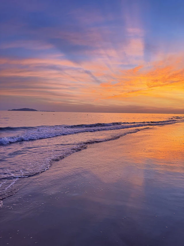 Pink and orange sunset reflected in the shoreline at Sanya Bay