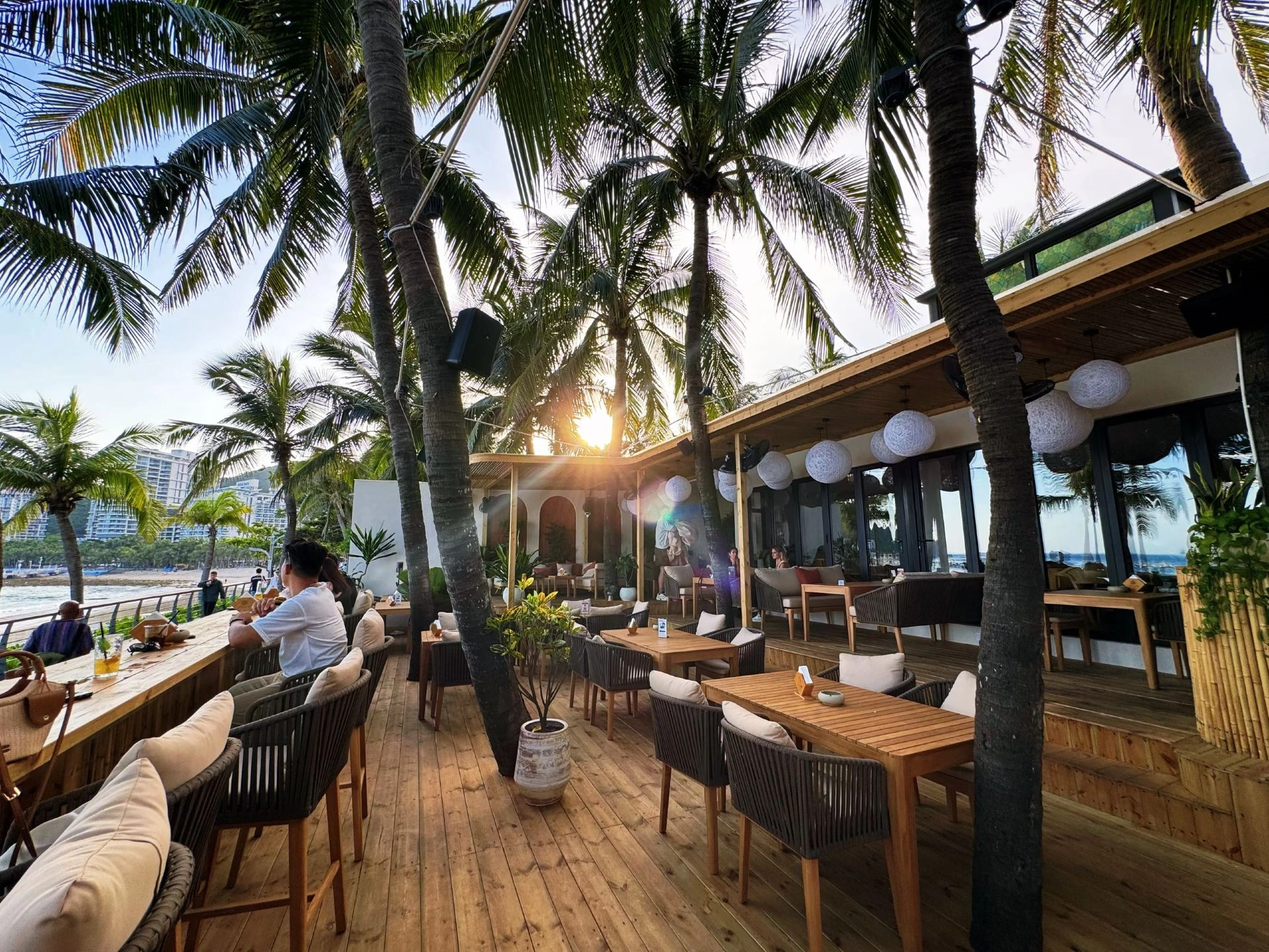 FreeGen’s timber terrace with tables, palms and views of Dadonghai